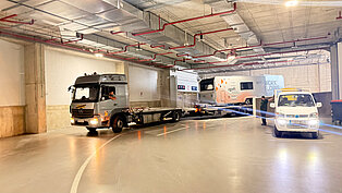 ein LKW mit Anhänger fährt durch eine moderne Tiefgarage