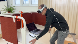 Michael hat die Apple Vision Pro auf und steht am Tisch aus der Scott Serie von Vitra